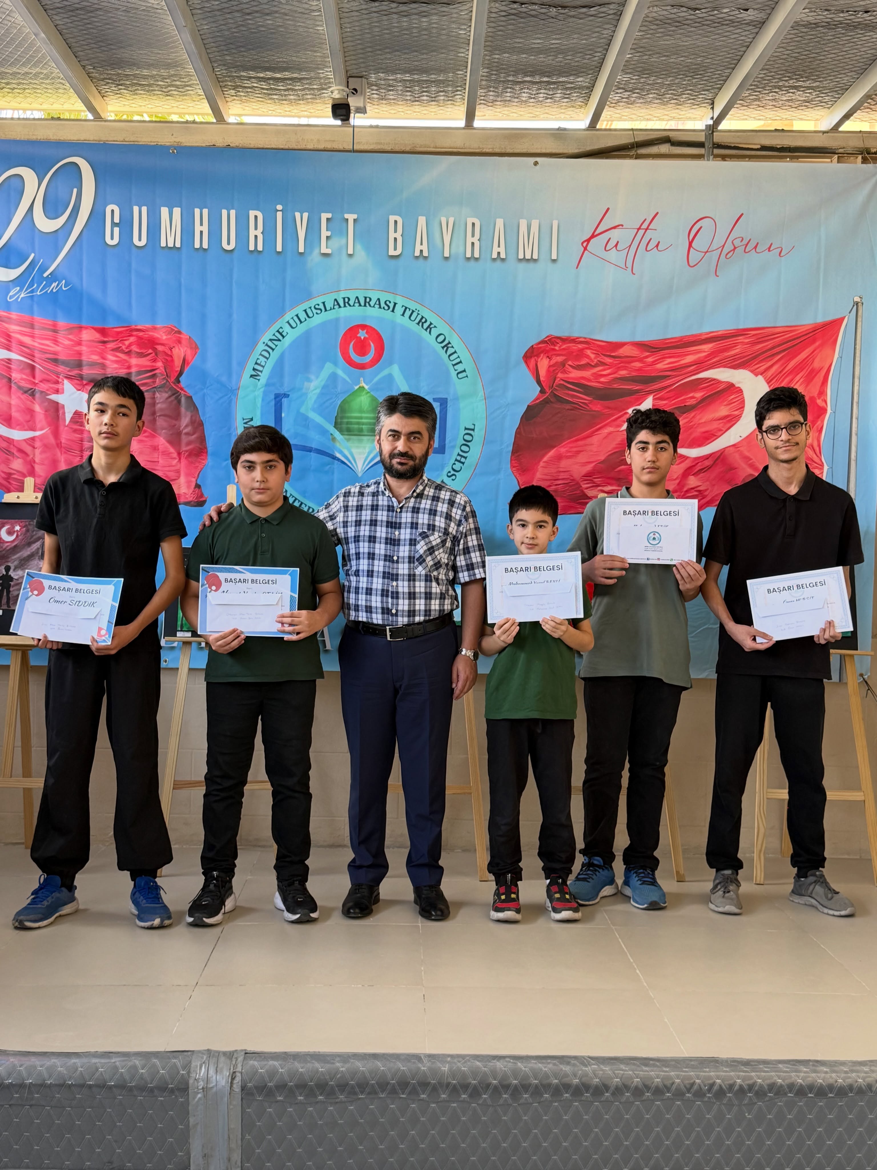 Medine Türk Okulunda kutlama sırasında sertifikalarını taşıyan öğrenciler