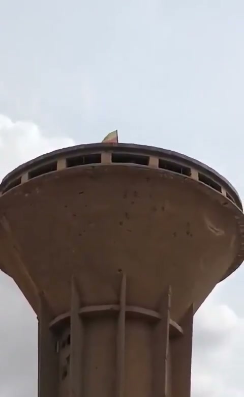شاب يصعد إلى خزان مياه لإنزال علم