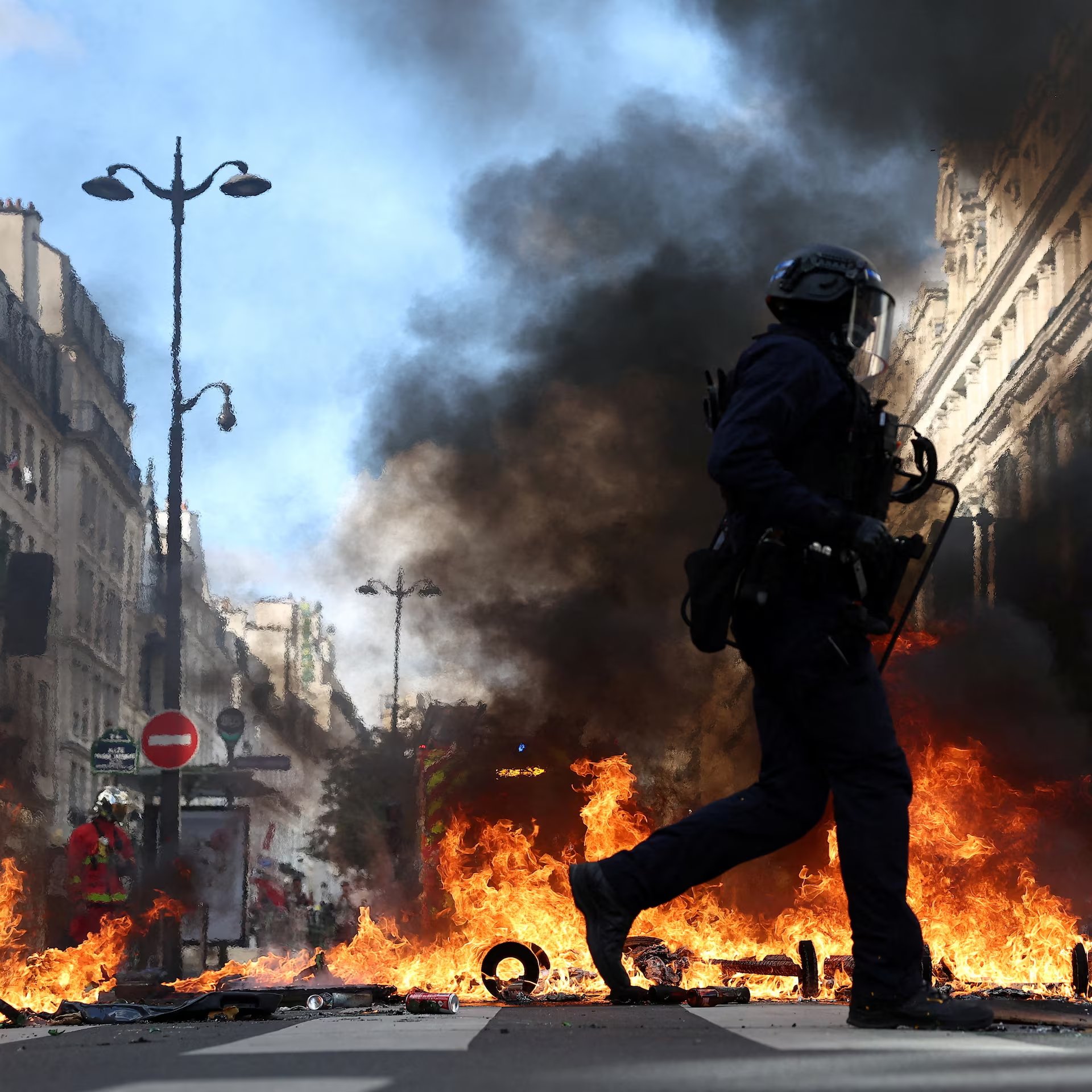 A police officer passes burning barriers during protests in Paris