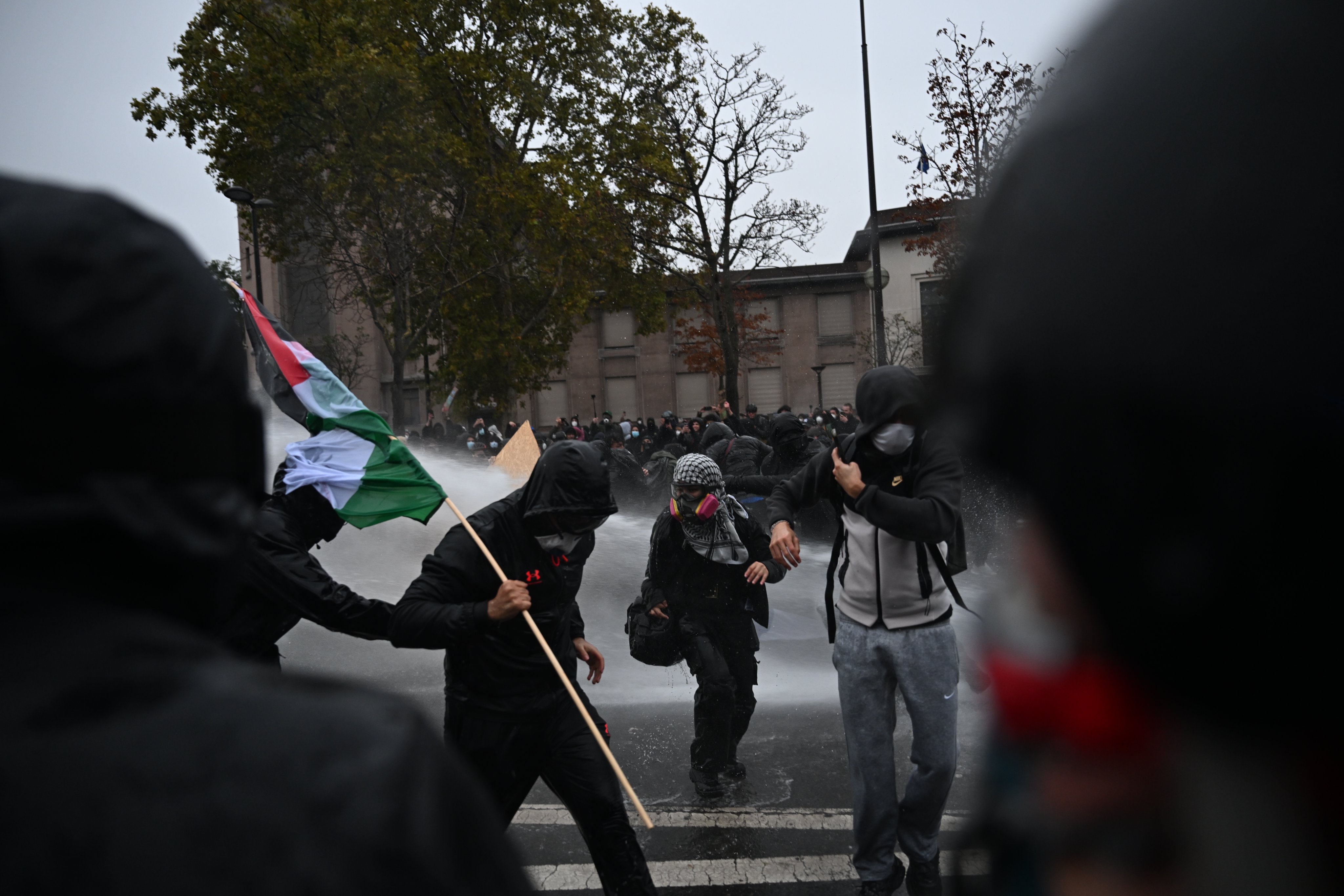 Protesters carrying a Palestinian flag are targeted with water cannon in Paris