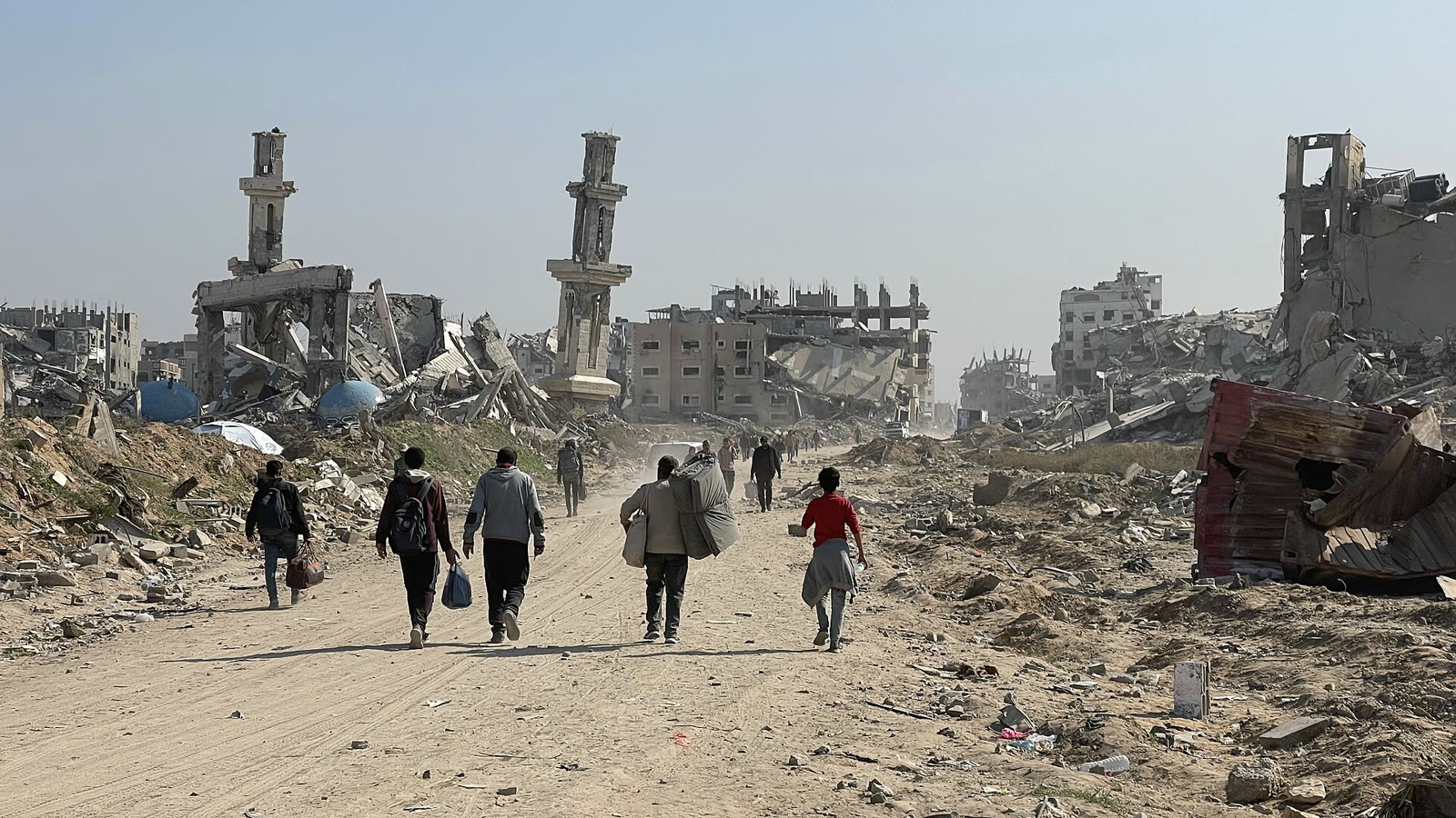 Palestinians walking among destroyed buildings in Gaza (archive)