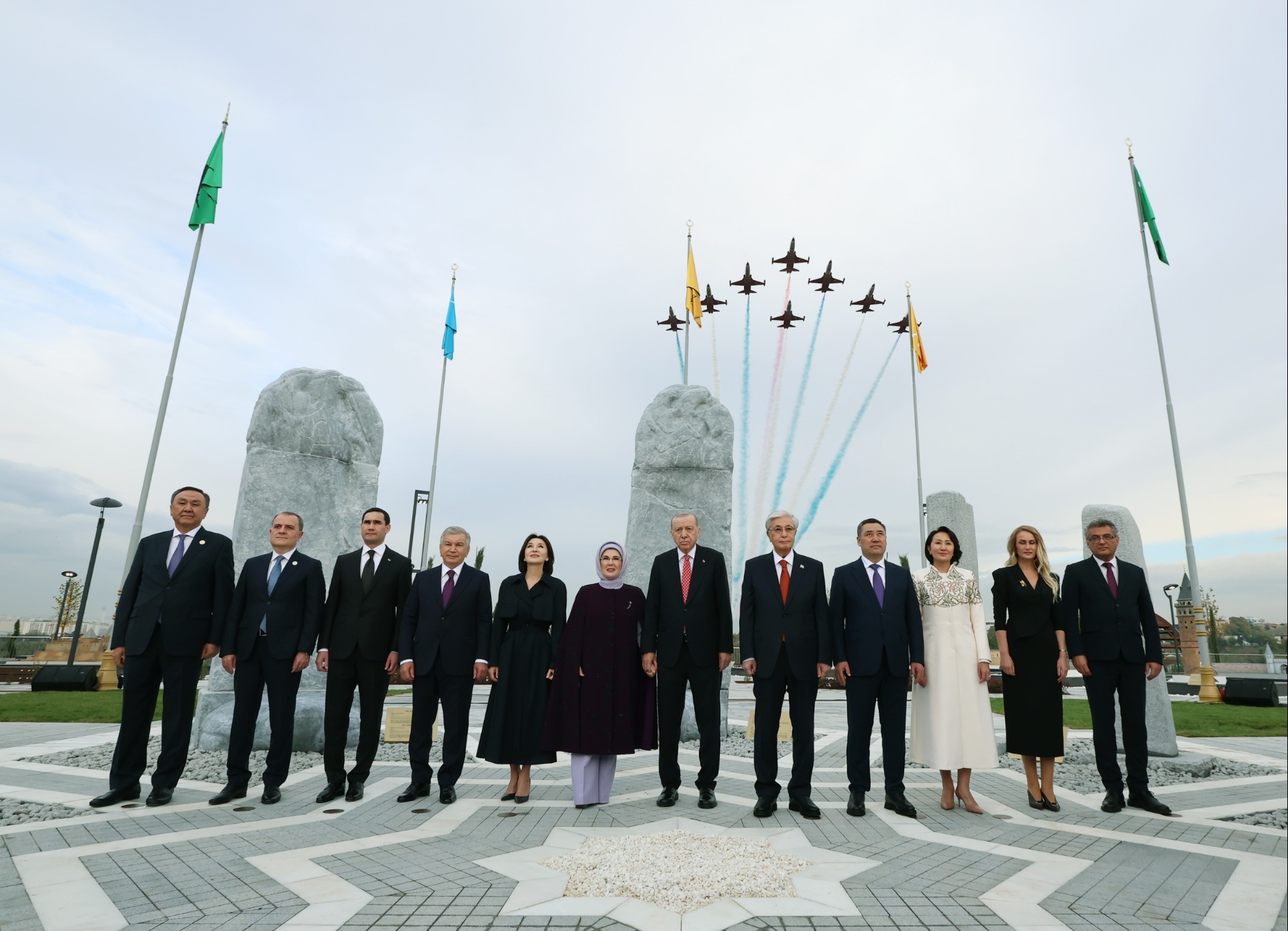 Turkic leaders stand before models of Orkhon inscriptions as the Turkish Stars fly overhead